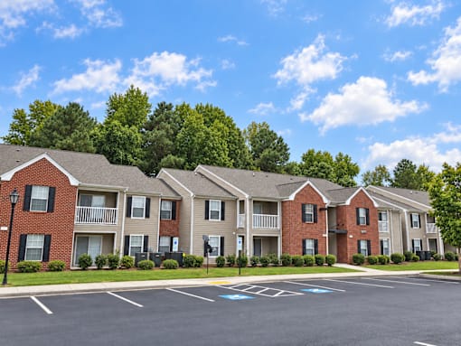 Apartment complex with a parking lot in front.