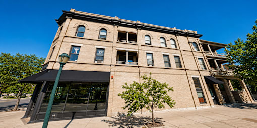 A large building with a black awning and a tree in front of it.