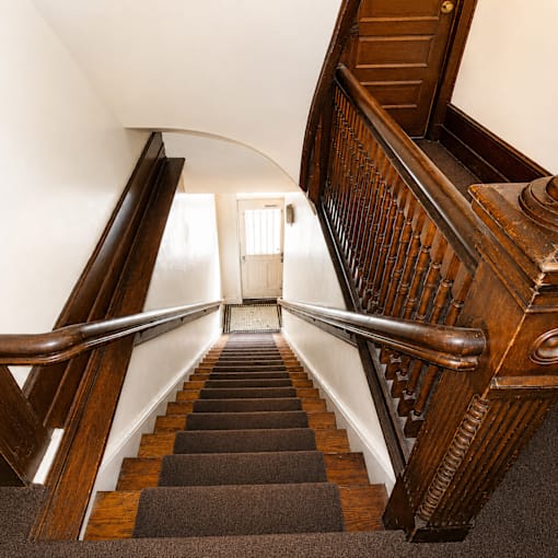 A staircase with a wooden handrail and a carpeted runner.