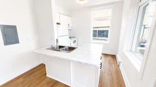 A kitchen with white cabinets and a window.