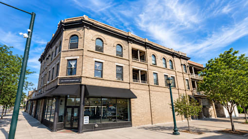 A large building with a black awning sits on a street corner.