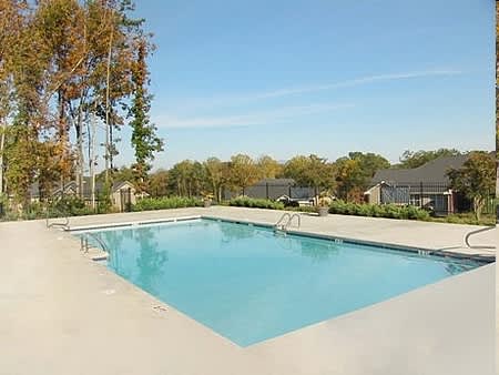 a swimming pool with trees and houses in the background