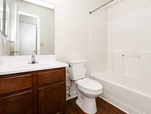 A white toilet sits in a bathroom next to a sink and a bathtub.