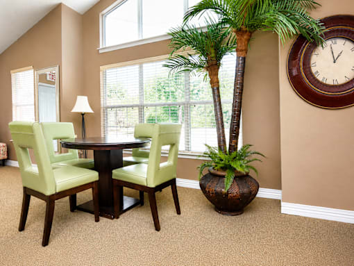 A dining room with a table, chairs and a clock on the wall.
