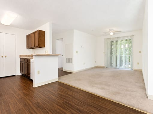 A spacious living room with a kitchen area in the background.
