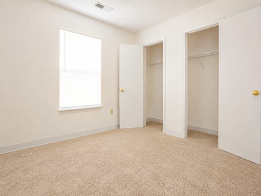 A room with a carpeted floor and a window.