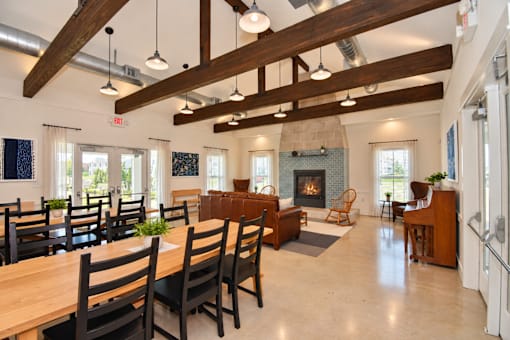 A clubhouse with large dining room with wooden chairs and a fireplace.
