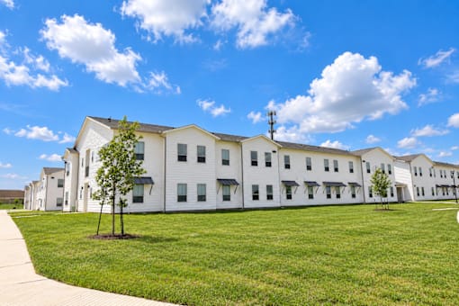 A white building with a green lawn in front and a clear blue sky above.