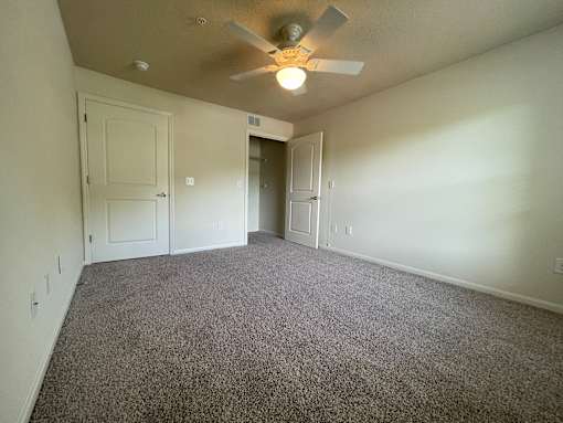A room with a ceiling fan and carpeted floor.