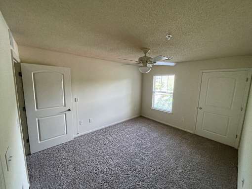 A room with a ceiling fan and carpeted floor.