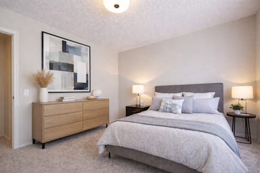 A bedroom with a large bed and a wooden dresser.