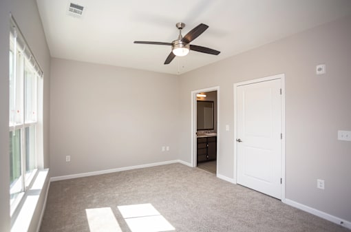 A room with a ceiling fan and a door.