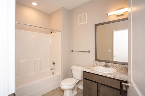 A white toilet sits in a bathroom next to a sink and a mirror.