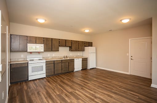 A kitchen with white appliances and wooden floors.