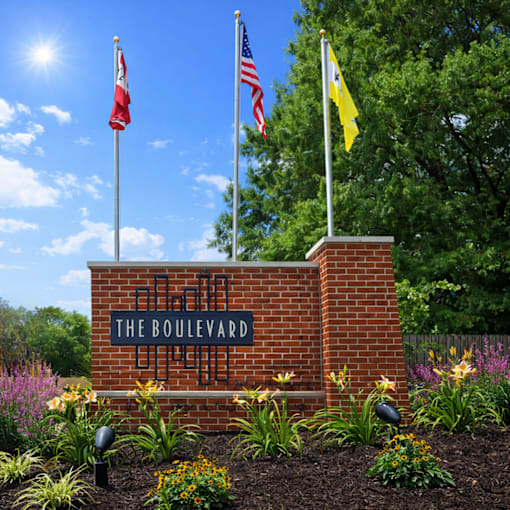 The Boulevard sign is mounted on a brick wall with three flags flying in the background.