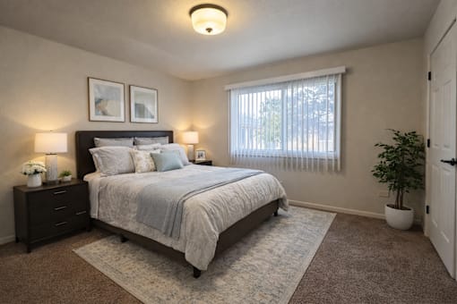 A bedroom with a bed, nightstands, and a window.