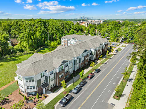 A large apartment complex is situated on a tree-lined street.