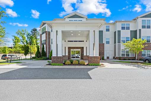 A large building with a front entrance and a parking lot in front.