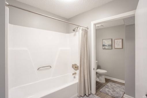 A white bathroom with a toilet and a bathtub.