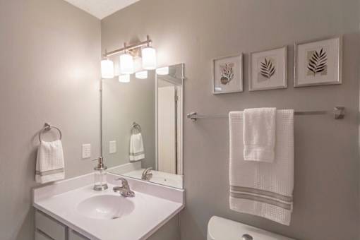 A white sink in a bathroom with a mirror and towel rack.