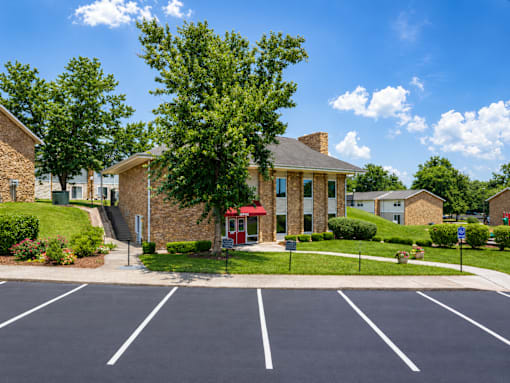 A parking lot in front of a building with a red awning.