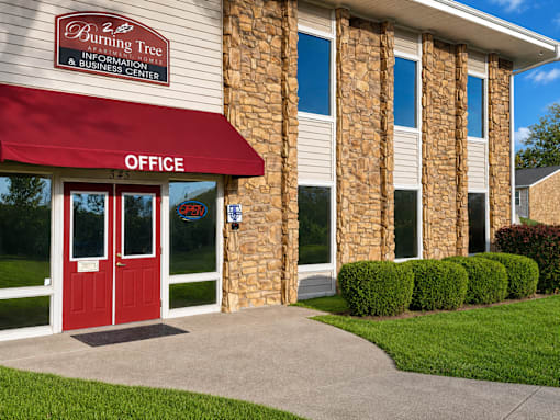 A building with a red awning and a sign that says "Burning Tree Information & Business Center".