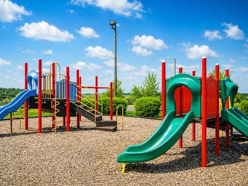 A playground with a green slide and a red and blue structure.