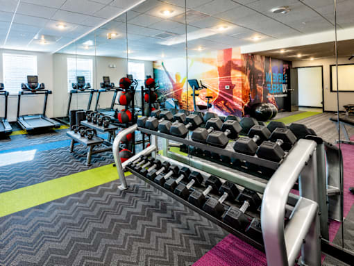 A gym with a variety of equipment including treadmills, weights, and exercise machines.