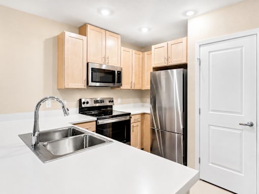 A kitchen with a sink, stove, and refrigerator.