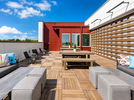 A wooden deck with a bench and chairs.