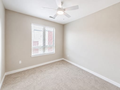 A room with a ceiling fan and a window with blinds.