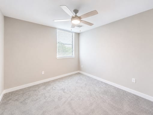 A room with a ceiling fan and carpeted floor.