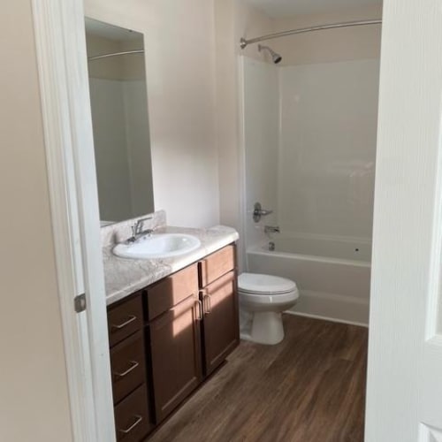 A white toilet sits in a bathroom with a white sink and a white bathtub.