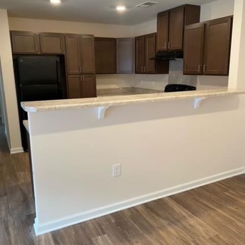 A kitchen with brown cabinets and a black fridge.