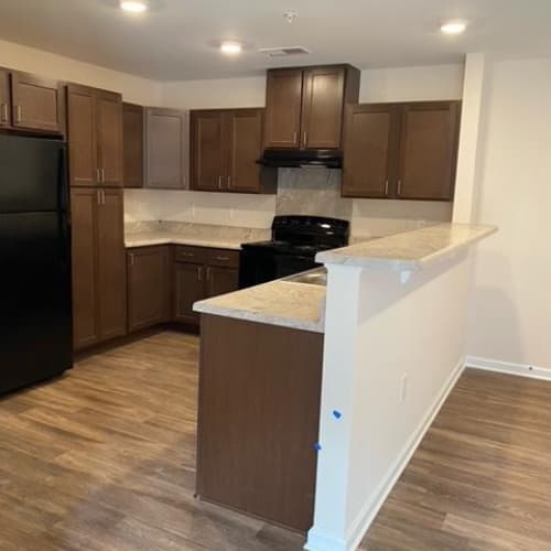 A kitchen with brown cabinets and a black refrigerator.