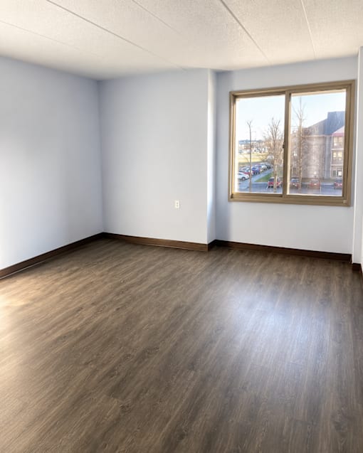 A room with a window and wooden flooring.