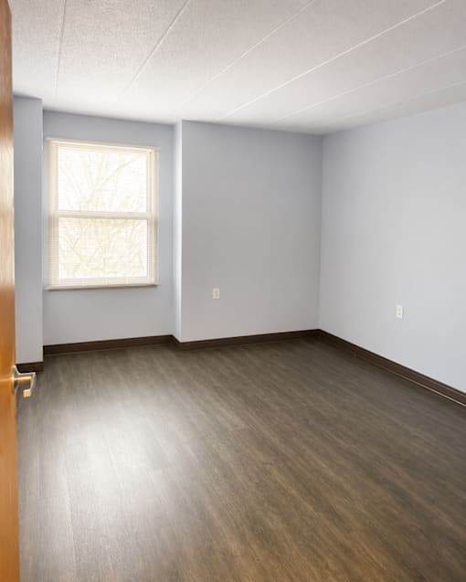 A room with a window and wooden flooring.