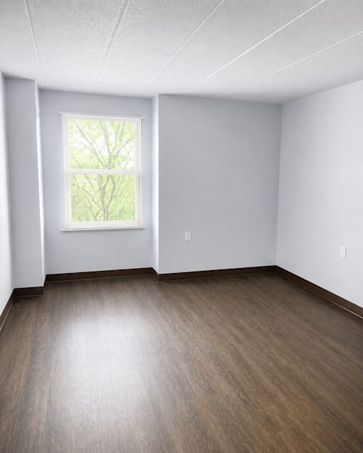 A room with a window and wooden flooring.