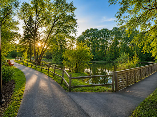 A paved road leads to a wooden bridge over a body of water.