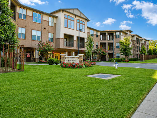 A large apartment complex with a green lawn in front.
