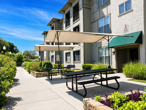 A sunny day at a residential building with a picnic table and benches.