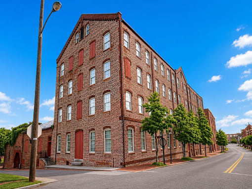 A long red brick building with many windows sits on a street corner.