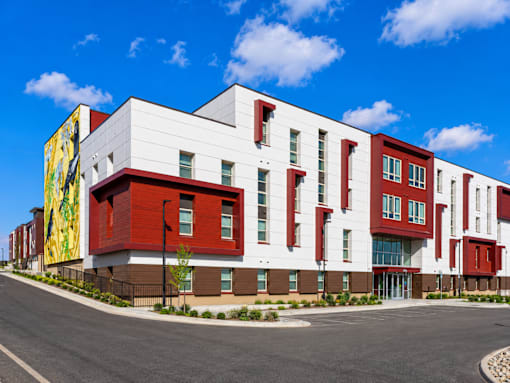 A modern building with a red and white facade and a yellow mural on the side.