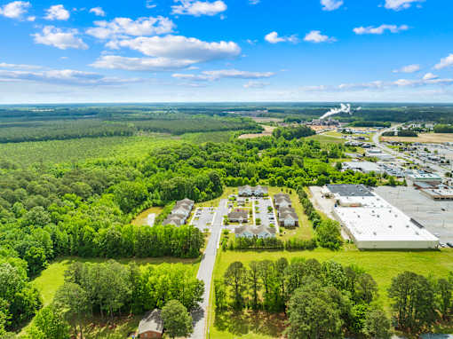 A bird's eye view of a residential area with a large green field and a road running through it.