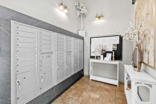 A row of white lockers in a room with a vase of flowers on a table.