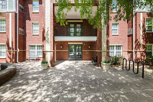 A red brick building with a courtyard in front.