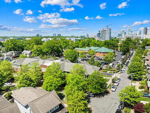 A suburban area with houses and trees in the foreground and a city skyline in the background.