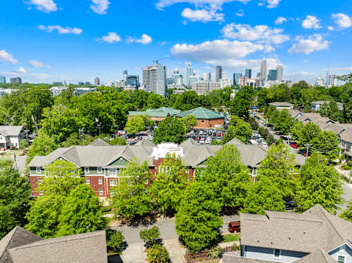 A suburban neighborhood with houses and trees in the foreground and a city skyline in the background.