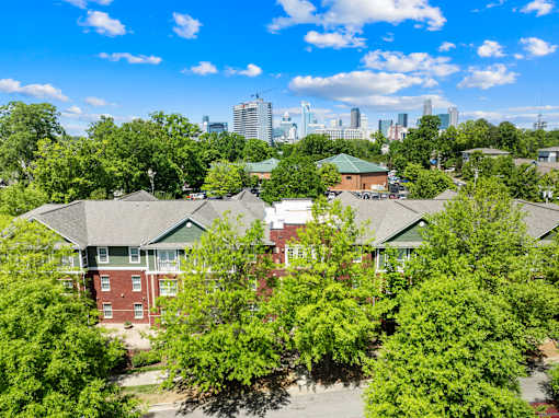 A view of a residential area with houses and trees in the foreground and a city skyline in the background.