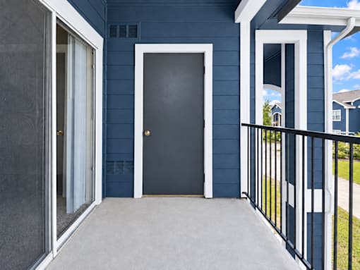 A black door is in the center of a blue house.